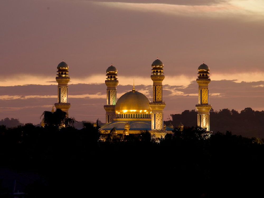 Sultan Omar Ali Saifuddien Mosque with golden dome and four minarets at dusk.